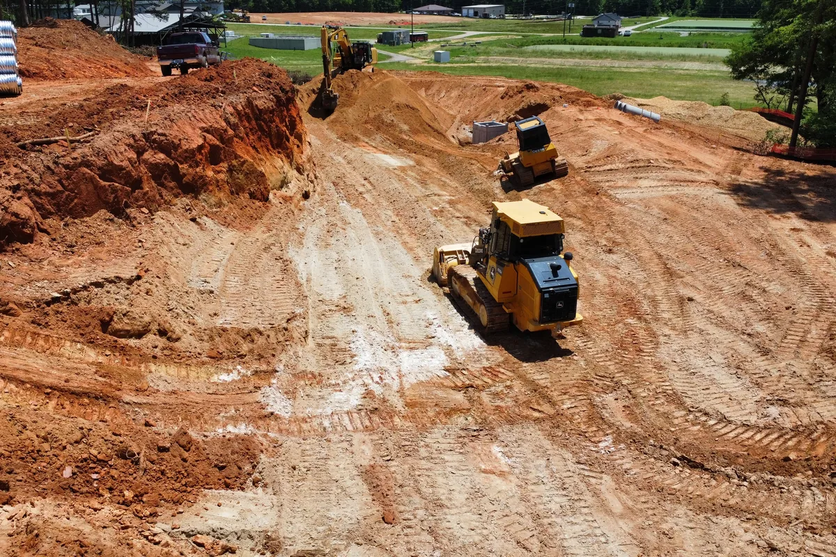 Dozer grading red clay on a large Georgia site with an excavator working the cut behind it