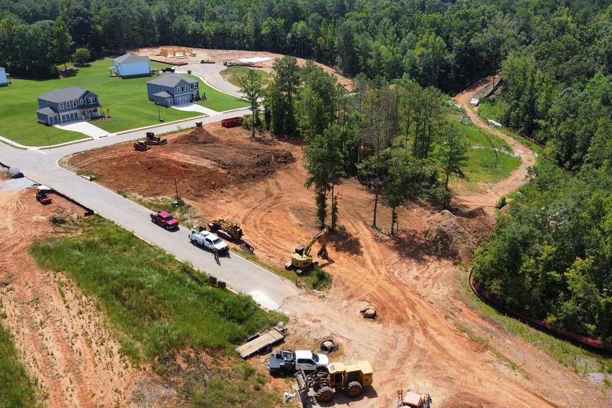 Aerial view of a subdivision lot being cleared and graded next to finished homes in Northeast Georgia